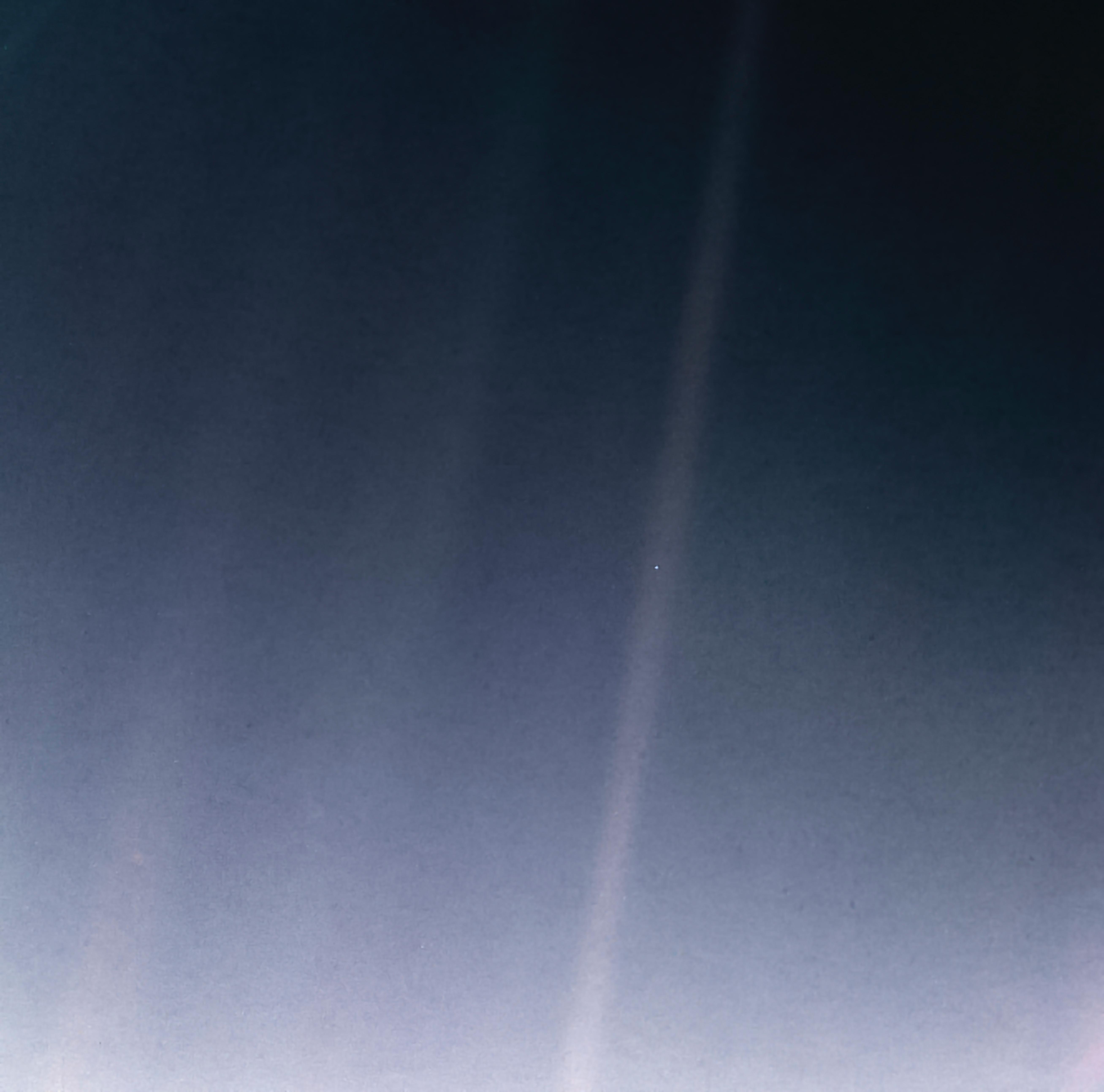 Image consists mainly of a light blue field with a shaft of sunlight running diagonally from the top of the frame to the bottom.  A lonely dot is seen about a third of the way down the sunlight shaft.